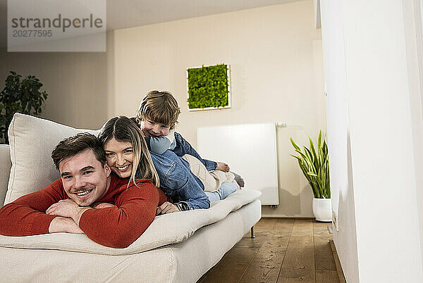 Happy family lying together on sofa at home