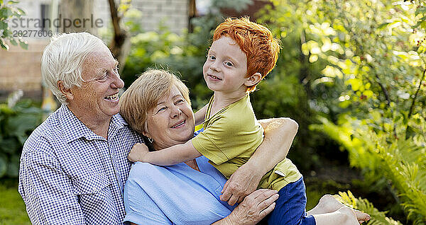 Glückliches älteres Paar  das Spaß mit Enkel im Garten hat