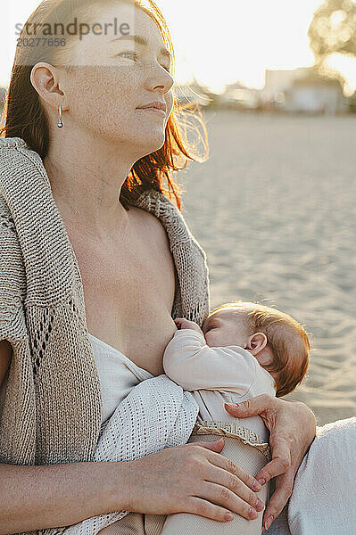 Frau stillt ihr Baby am Strand