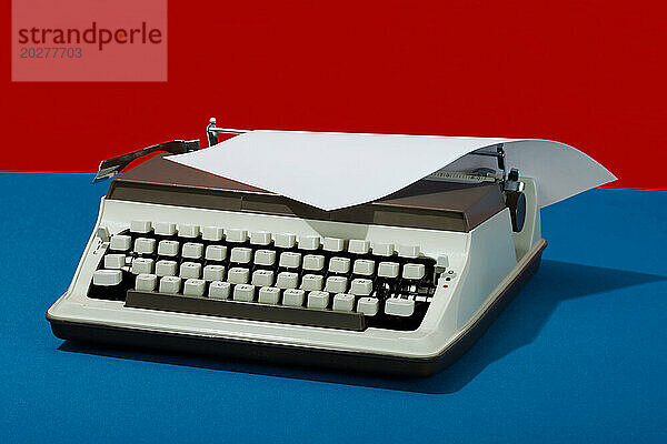 Retro-Schreibmaschine mit Papier vor farbigem Hintergrund