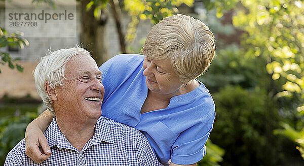 Glücklicher älterer Mann verbringt Freizeit mit Frau im Garten