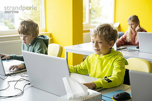 Blonde Jungen benutzen Laptops und lernen im Klassenzimmer Computerprogrammierung