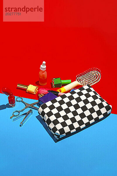 Studio shot of various cosmetics falling out of checked purse