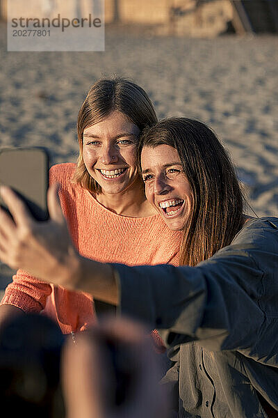 Fröhliche Freunde machen gemeinsam ein Selfie am Strand