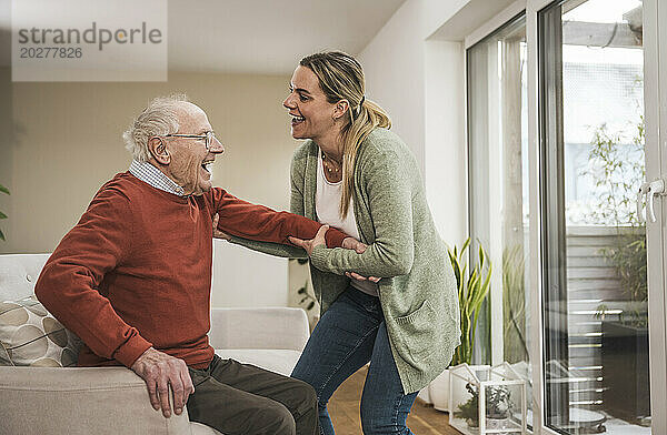 Heimpfleger kümmert sich um älteren Mann im Wohnzimmer