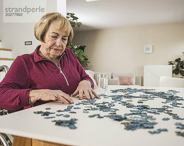 Ältere Frau spielt Puzzlespiel am Tisch