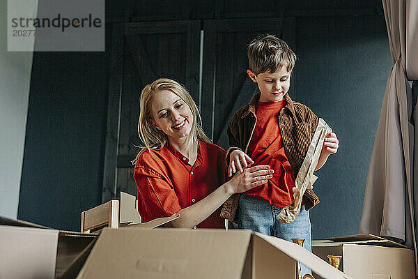 Glückliche Frau mit Sohn beim Verpacken von Kartons
