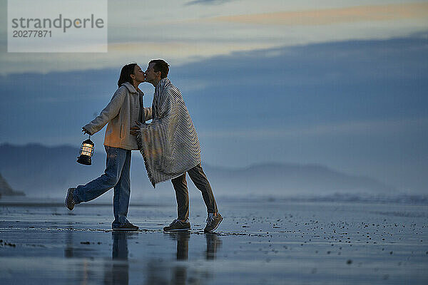 Junge Freundin und Freund küssen sich am Meeresstrand
