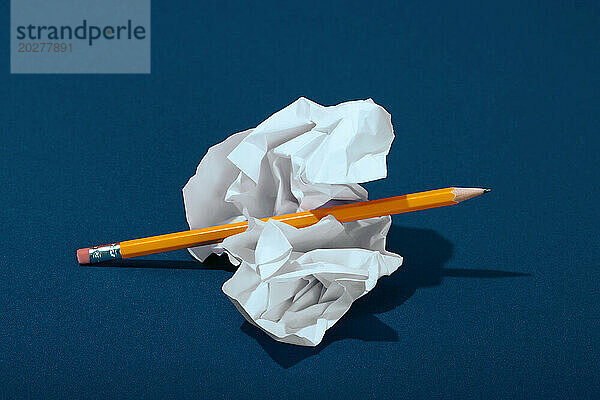 Zerknittertes Papier mit Bleistift auf blauem Hintergrund