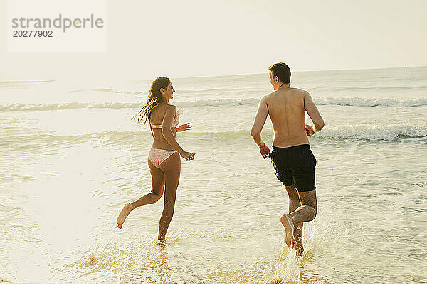 Carefree couple running in water at beach