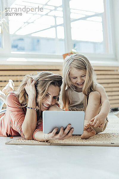 Smiling girl with mother using tablet PC at home
