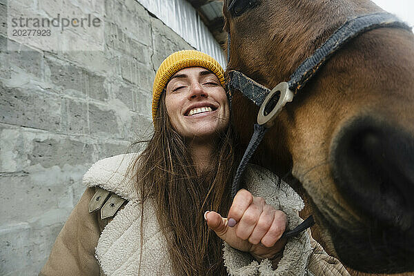 Lächelnde Frau mit Pferd auf dem Bauernhof
