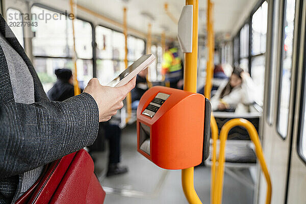 Frau kauft Fahrkarte per Smartphone in der Straßenbahn