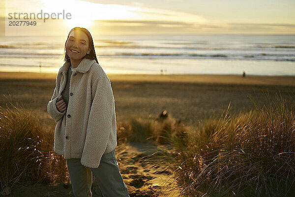 Lächelnde junge Frau  die am Meeresstrand steht