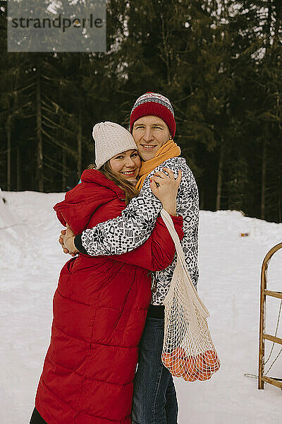 Glückliches Paar umarmt sich im Winterwald