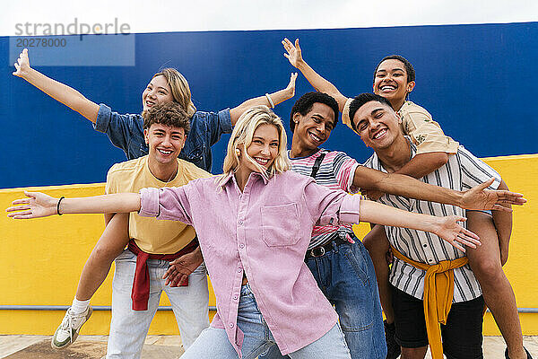 Group of young friends with colorful clothing posing happily in front of wall