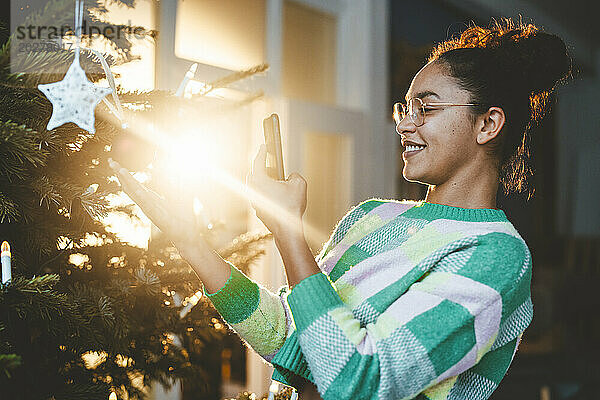 Junge Frau fotografiert Weihnachtsbaum über Smartphone