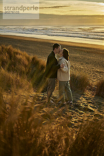Junges Paar küsst sich am Meeresstrand
