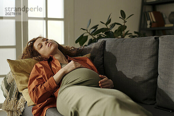 Pregnant woman sleeping on sofa in living room