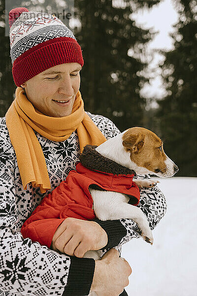 Man and dog wearing warm clothes in winter forest