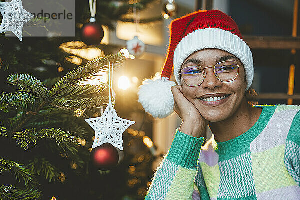 Lächelnde Frau mit Weihnachtsmütze an Weihnachten zu Hause