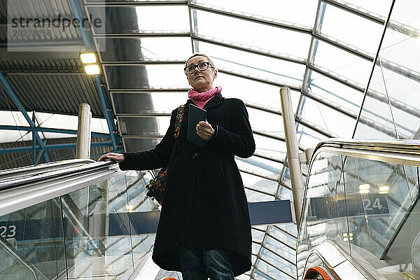 Geschäftsfrau bewegt sich auf Rolltreppen am Bahnhof hinunter
