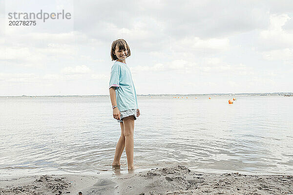 Glückliches Mädchen  das am Ufer des Sees steht