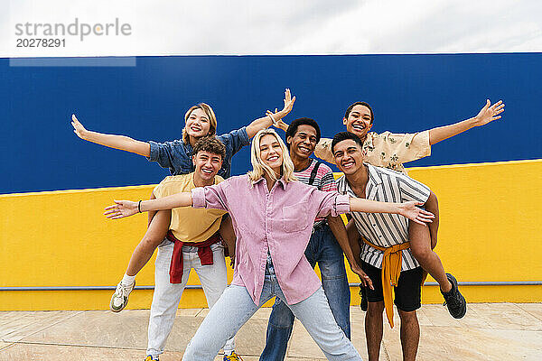Group of young friends with colorful clothing posing happily in front of wall