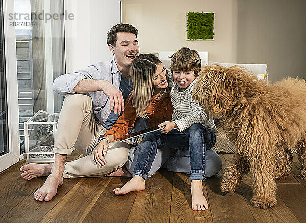 Glückliche Familie genießt es mit Hund zu Hause