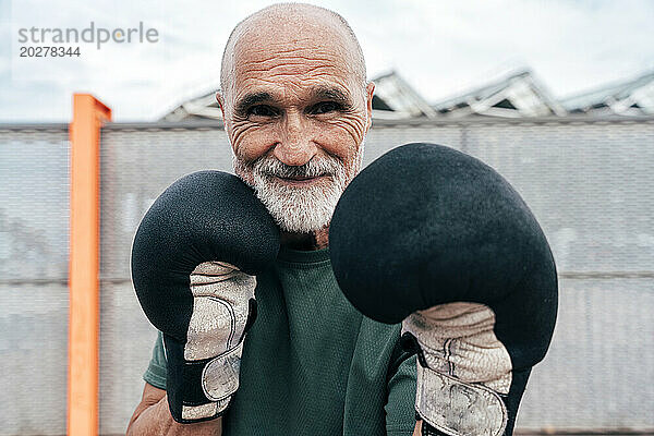 Lächelnder älterer Mann  der mit Boxhandschuhen übt