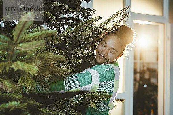 Junge Frau umarmt Weihnachtsbaum
