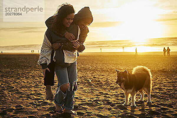 Glückliches Paar genießt es mit Hund am Strand