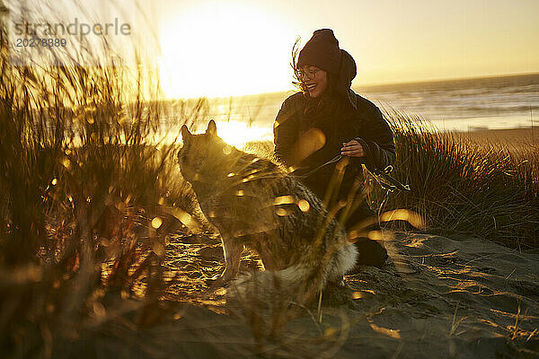 Glückliche Frau spielt mit Husky-Hund am Strand
