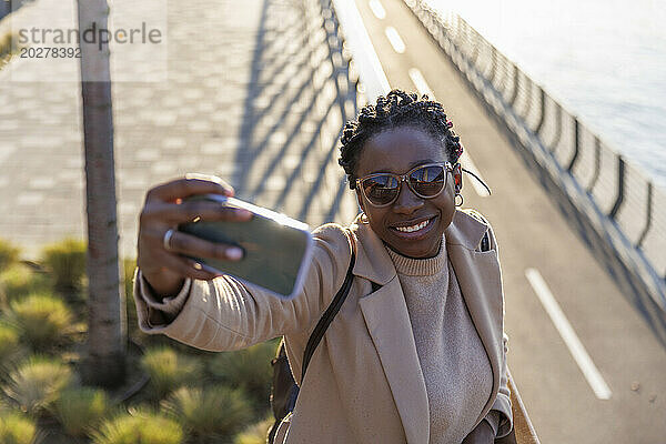 Lächelnde Frau  die ein Selfie mit dem Mobiltelefon macht