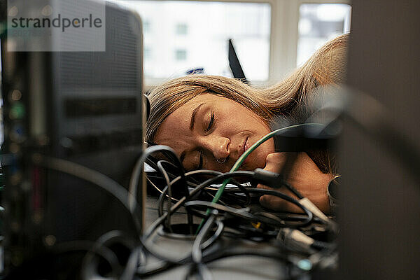 Exhausted businesswoman sleeping at desk in office