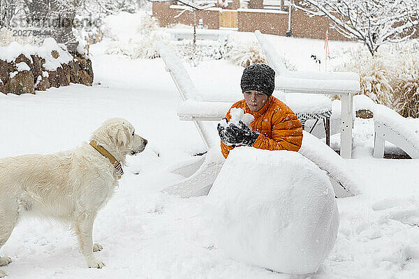 Junge baut mit seinem Hund einen Schneemann