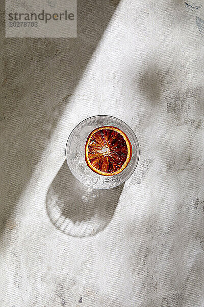 Draufsicht auf ein Glas Tequila mit Blutorangenscheibe auf Marmoroberfläche