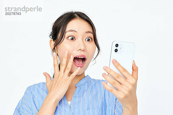 Eine Frau hält ein Mobiltelefon mit offenem Mund