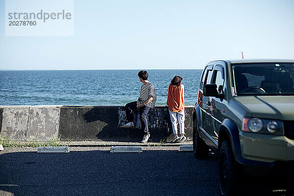 Ein Paar sitzt am Straßenrand in der Nähe des Ozeans