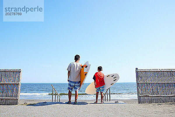 Familie mit Surfbrettern am Strand