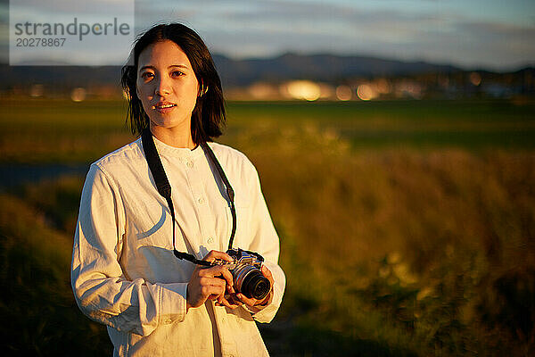 Eine Frau hält eine Kamera auf einem Feld