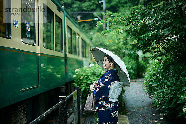 Eine Frau im Kimono hält einen Regenschirm
