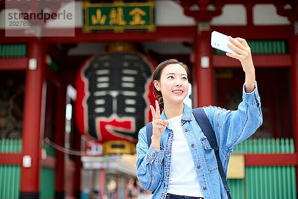 Eine Frau macht ein Selfie vor einem Tempel