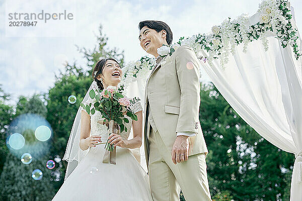 Ein frisch verheiratetes Paar steht unter einem Hochzeitsbogen