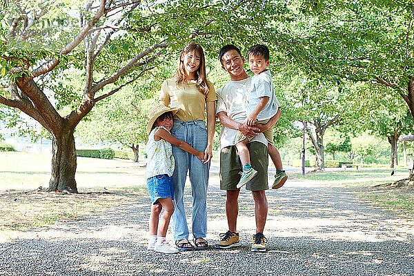 Eine Familie steht in einem Park unter Bäumen