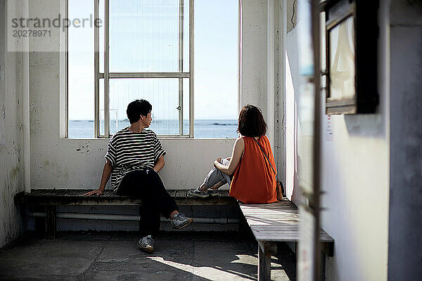 Ein Paar sitzt auf einer Bank und blickt auf das Meer