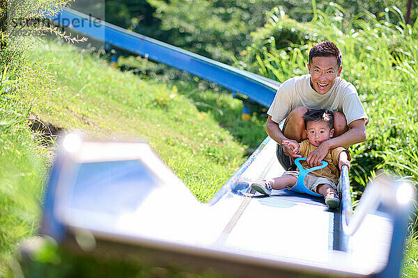 Ein Mann und ein Kind auf einer Rutsche in einem Park