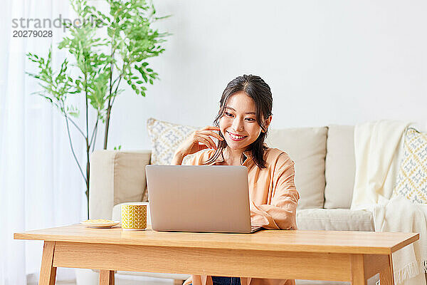 Asiatische Frau benutzt Laptop im Wohnzimmer