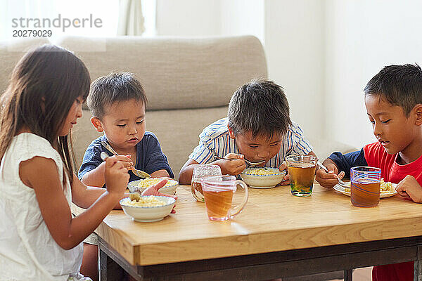 Vier Kinder sitzen an einem Tisch und essen
