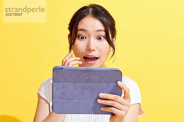 Eine Frau hält einen Tablet-Computer mit einem überraschten Gesichtsausdruck